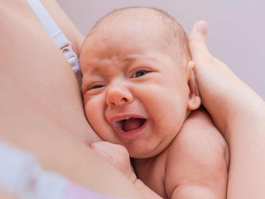 Baby weint an der Brust