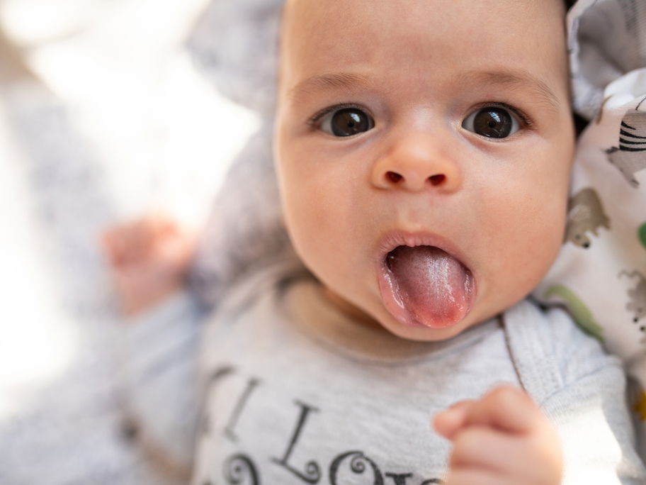 Ein kleines Baby streckt seine Zunge raus.
