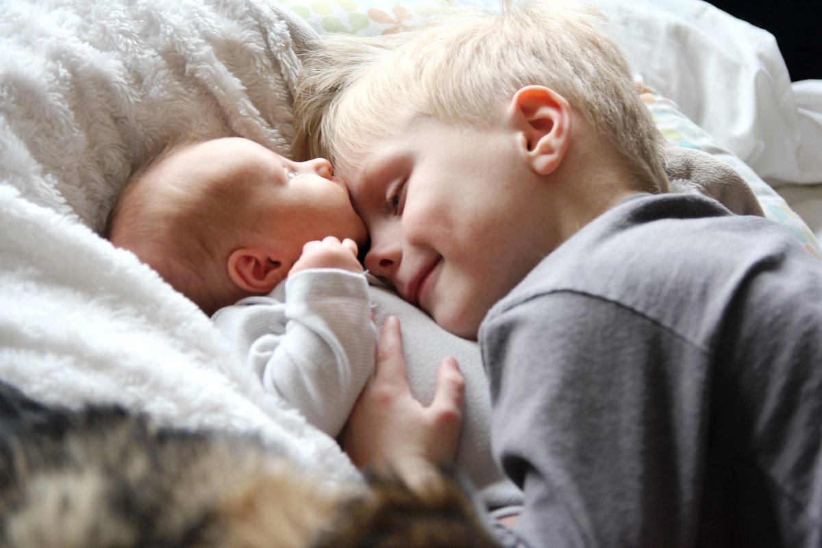 Junge kuschelt mit Baby