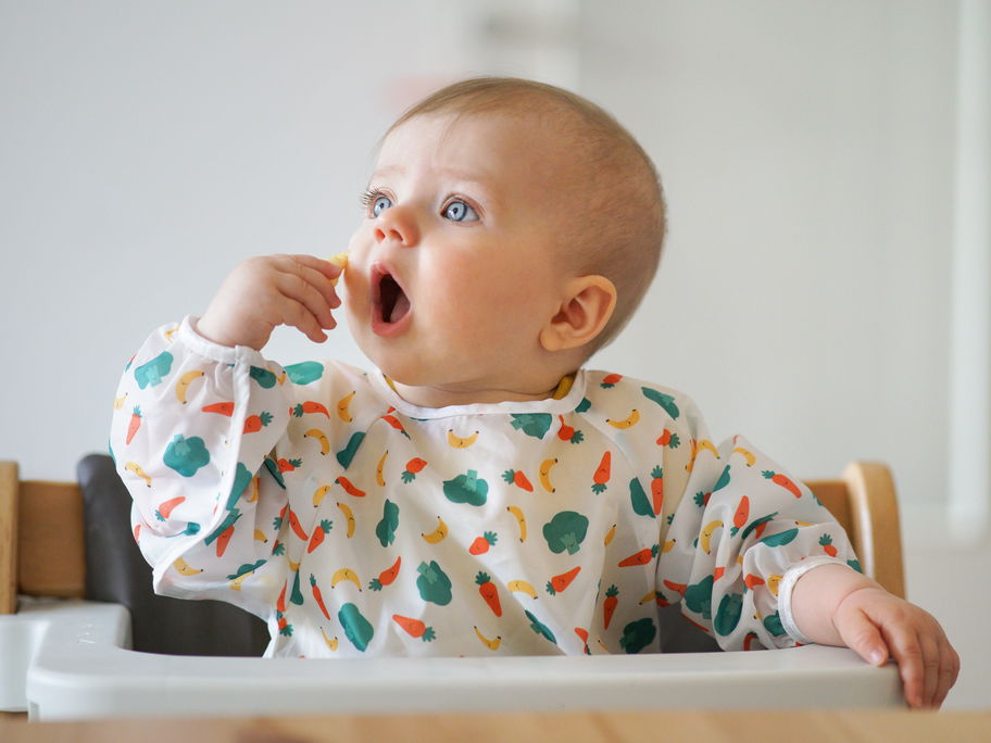 Baby steckt sich etwas zu Essen in den Mund.
