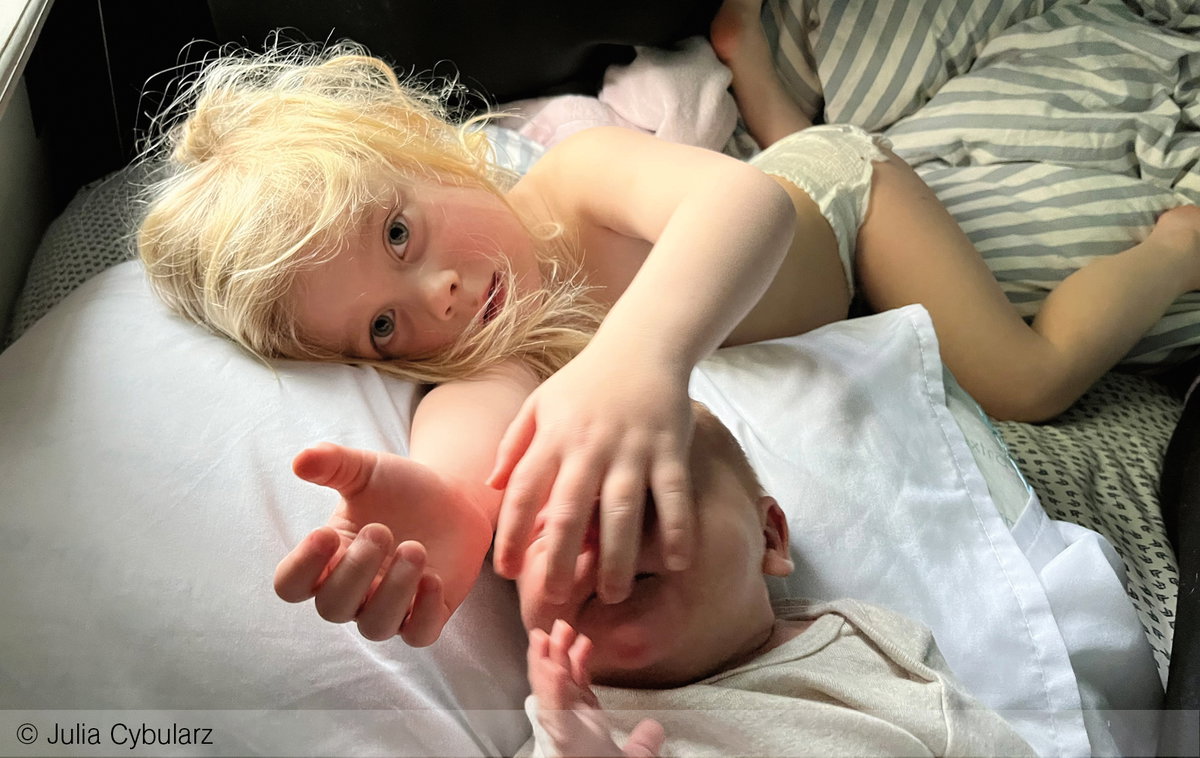 Zwei Geschwister liegen zusammen im Bett
