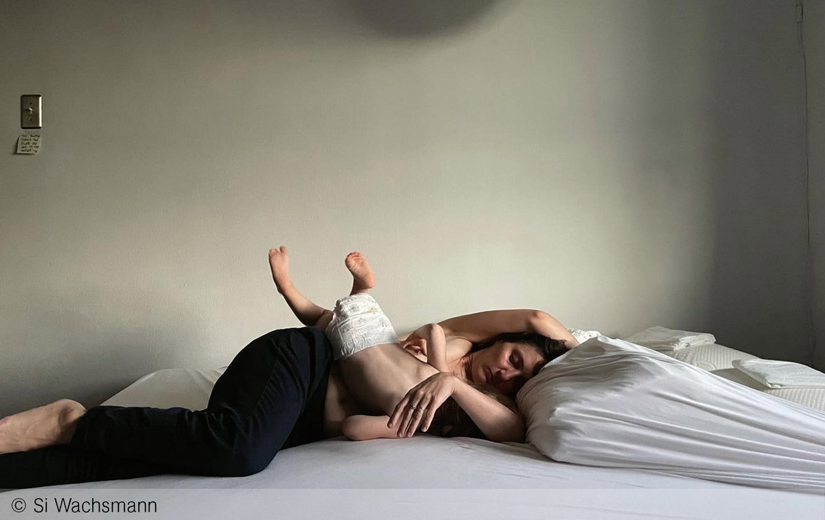 Eine stillende Frau mit Kleinkind im Bett
