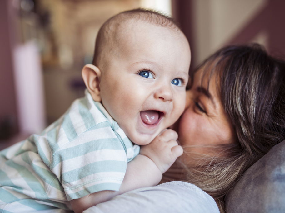 Mama küsst ihr lachendes Baby