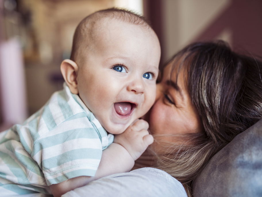Ein Baby liegt lachend auf seiner Mutter.