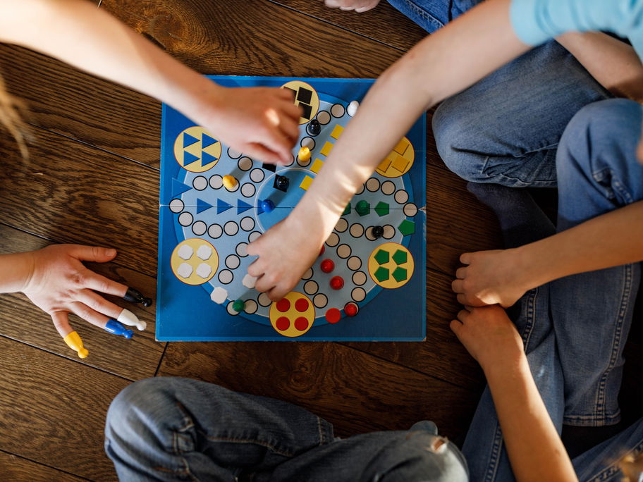 Viele Kinder sitzen um ein Gesellschaftsspiel herum.