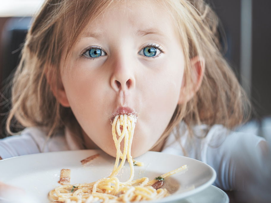 Ein Mädchen isst Spaghetti.