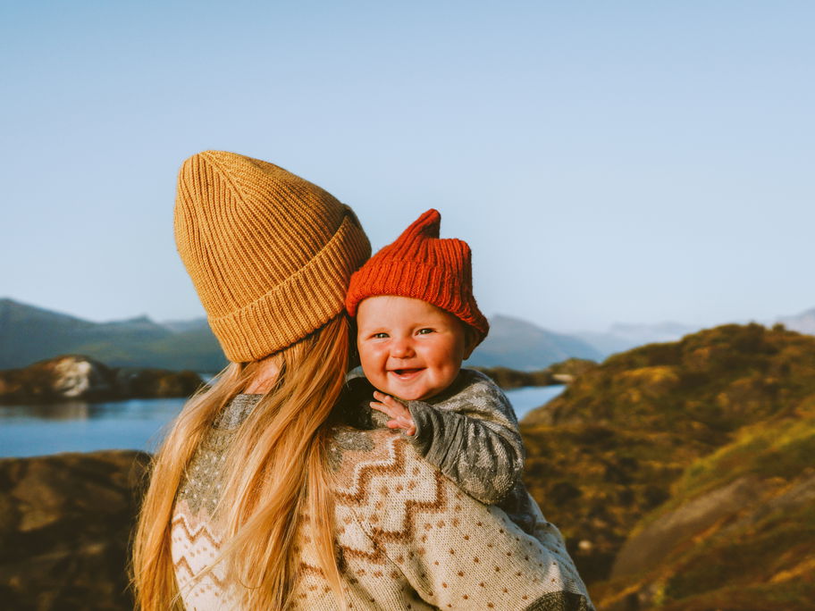 Ein Mutter hält ihr Baby und beide tragen einen Norweger-Pulli.