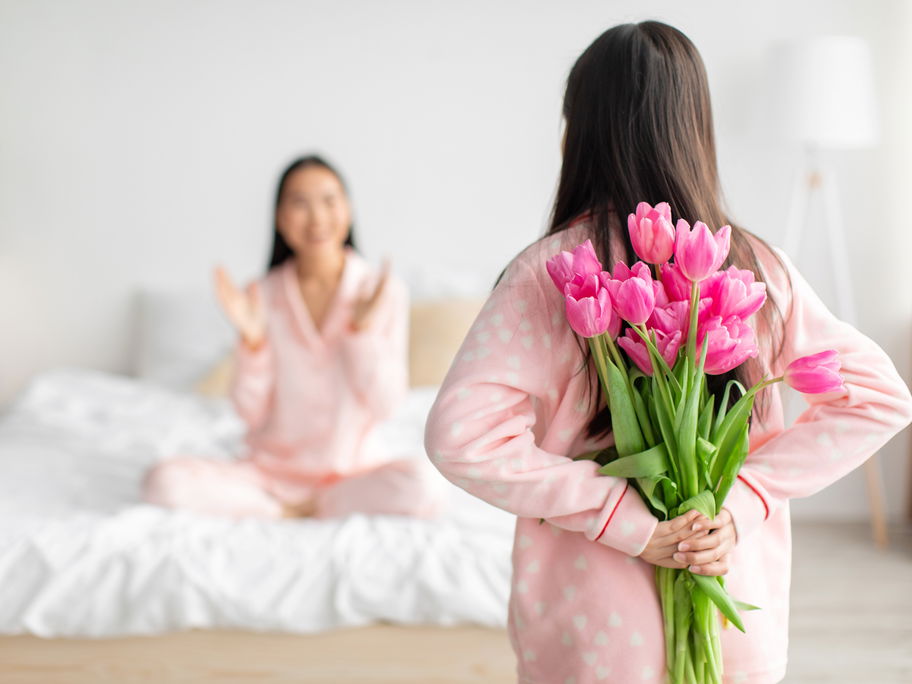 Mädchen versteckt Blumen für ihre Mutter hinter ihrem Rücken