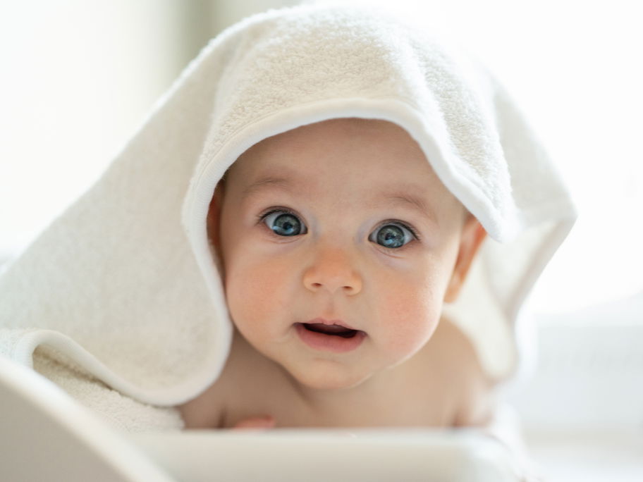 Ein Baby versteckt sich unter einem Handtuch.