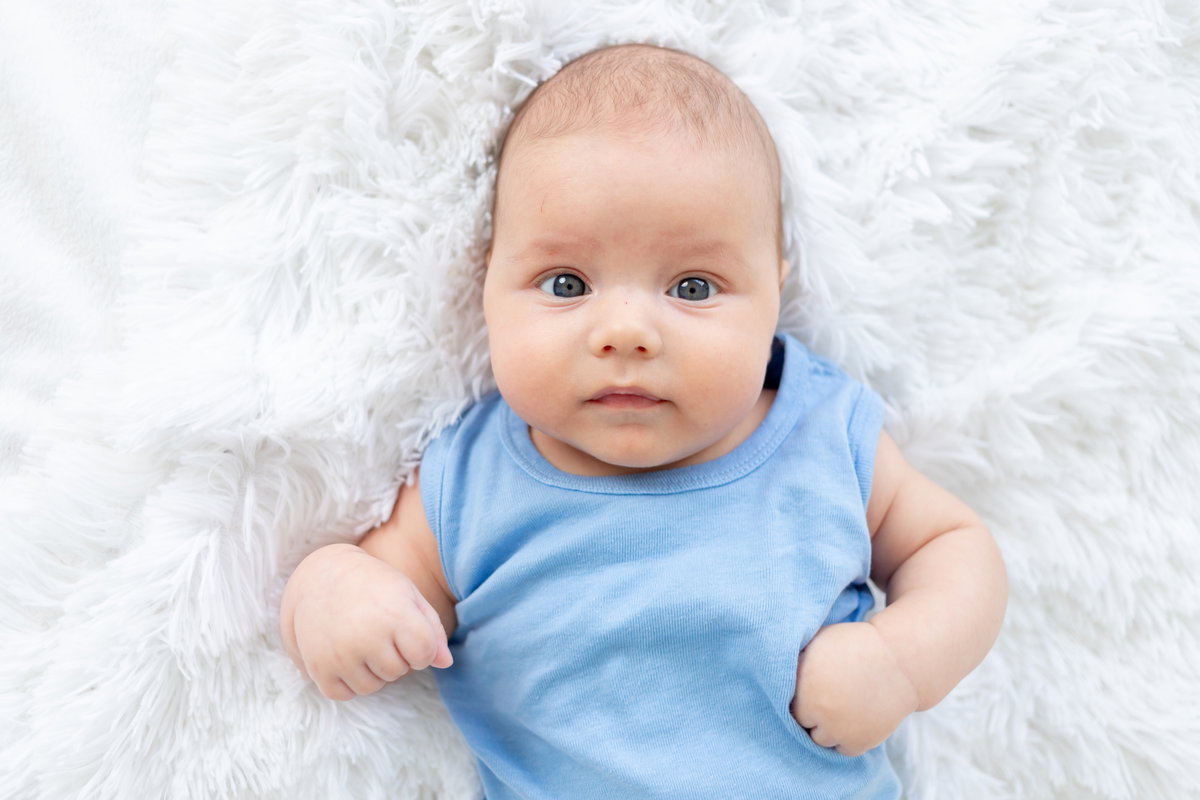 Baby in blauem Body auf einem Fell