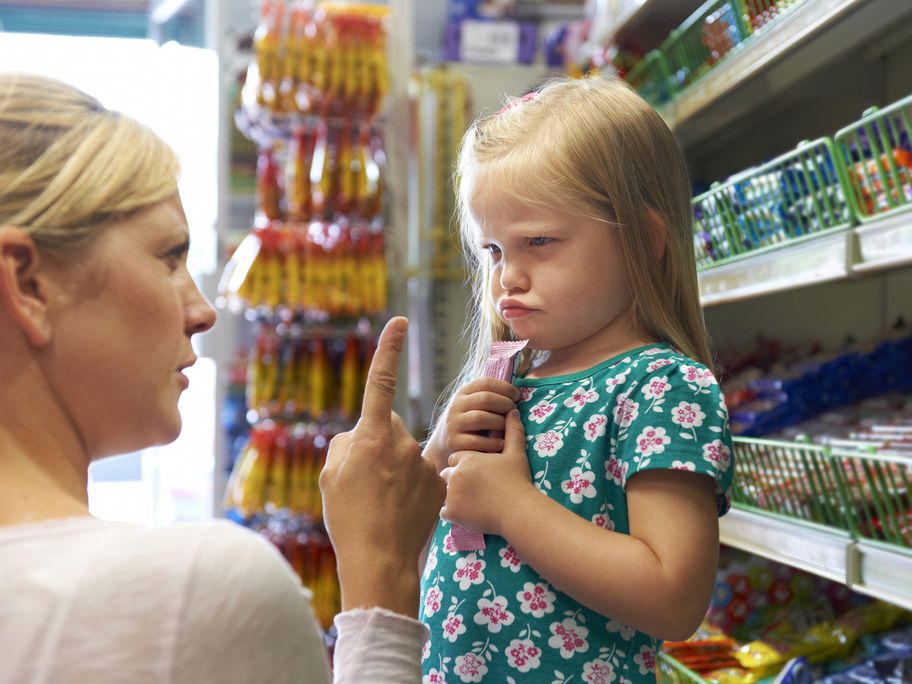 Mama schimpft mit ihrer Tochter, die im Supermarkt einen Riegel geholt hat