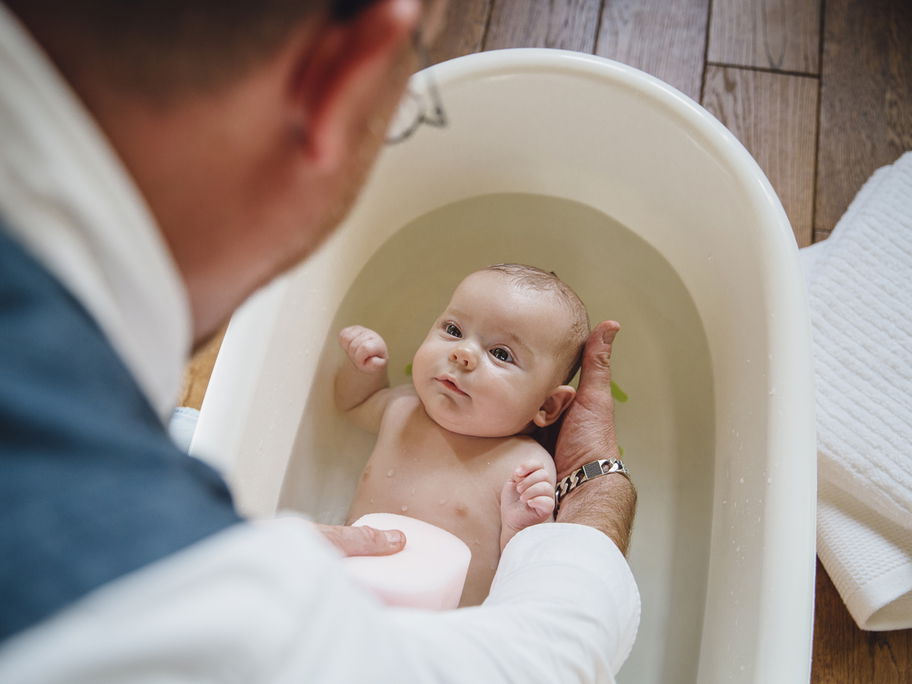 Ein Vater badet sein Baby in deiner Babybadewanne