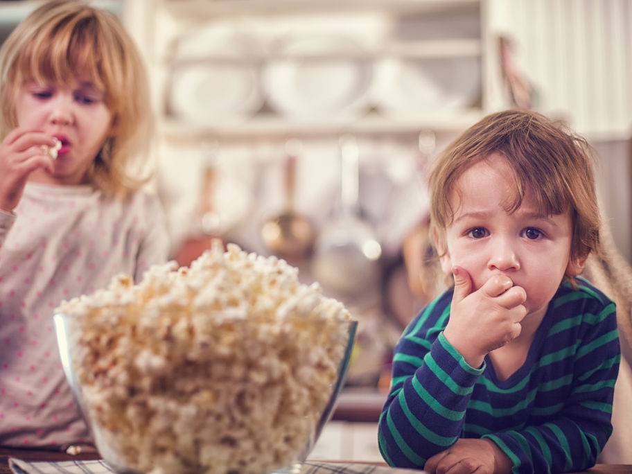 Zwei kleine Kinder essen Popcorn
