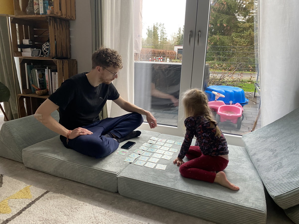 Papa und Tochter spielen Memory auf einem Spielsofa