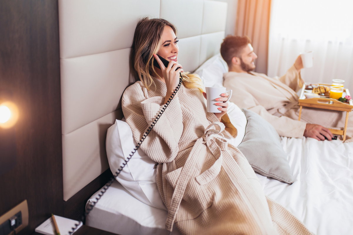 Ein Pärchen genießt den Roomservice im Hotelbett