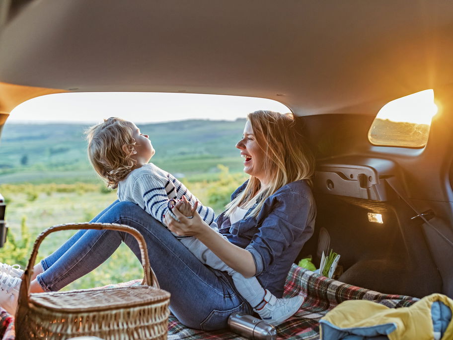 Mutter und Kind sitzen im Van und haben ein Picknick dabei.