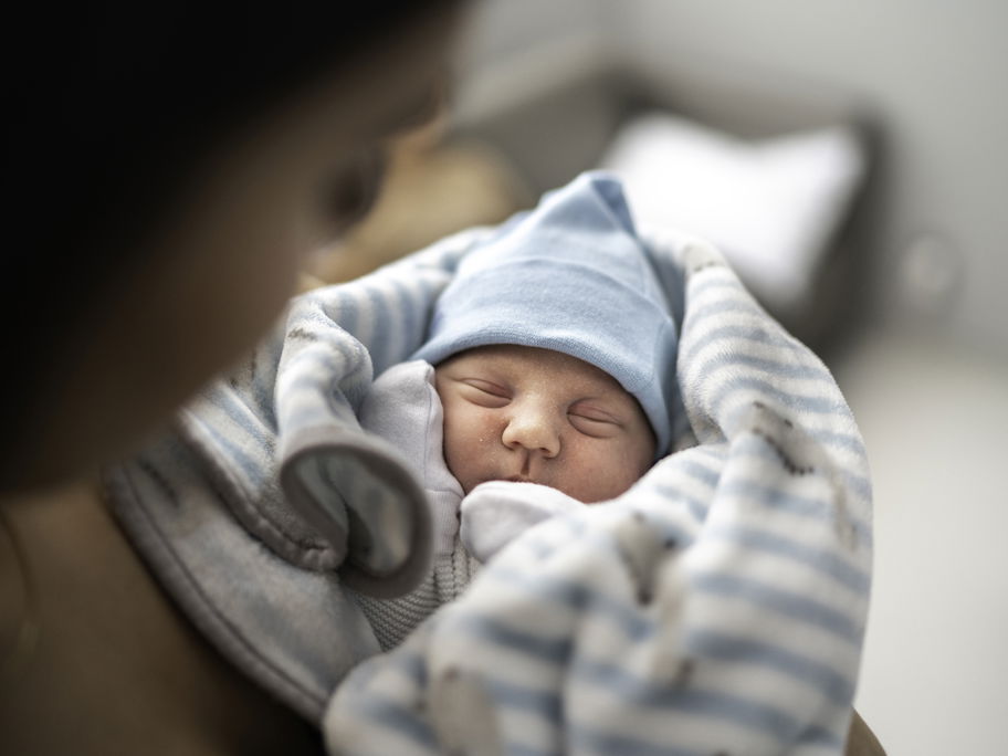 Ein kleines Baby liegt in den Armen seiner Mutter.
