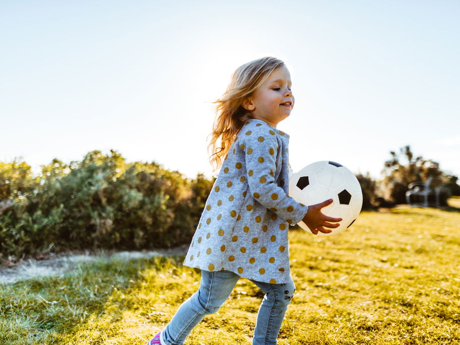 Ein Mädchen spielt mit einem Ball.