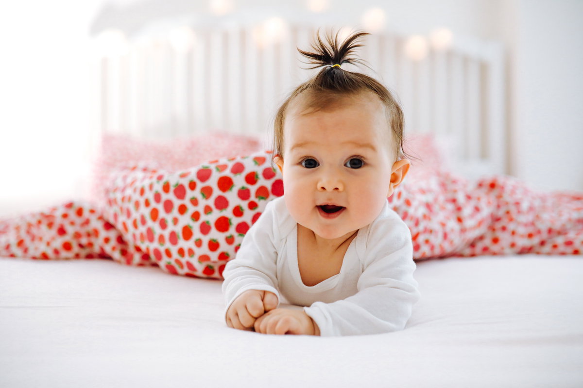 Ein Baby liegt lächelnd auf dem Bett.
