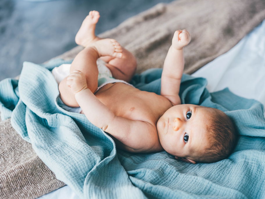 Ein Baby liegt auf einem blauen Tuch.
