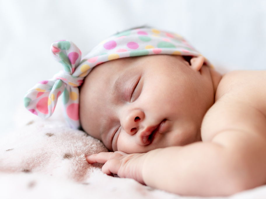 Ein Baby liegt schlafend auf dem Bauch.