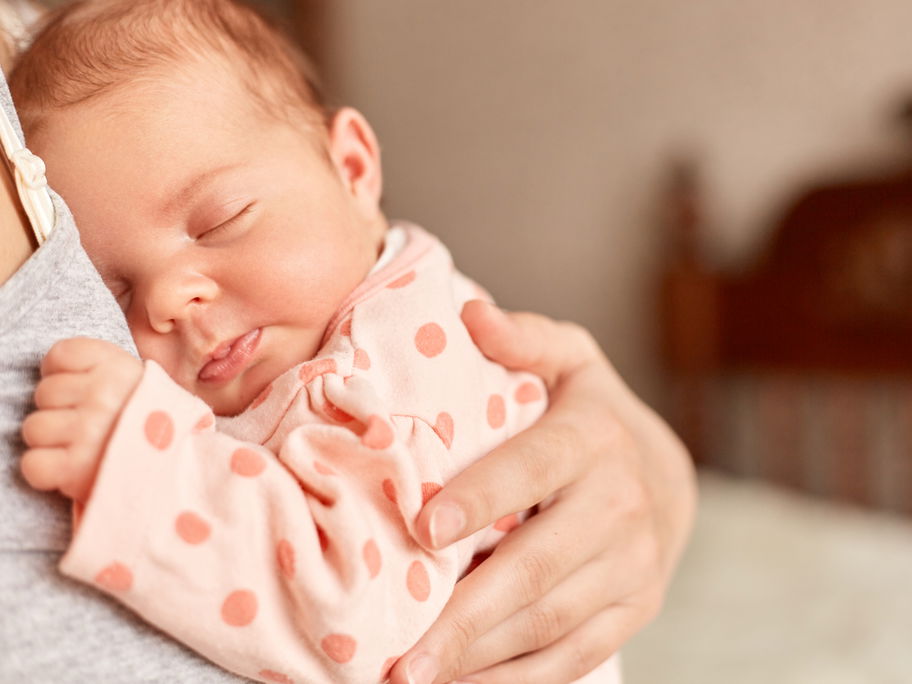 Neugeborenes Baby kuschelt auf dem Arm seiner Mutter.
