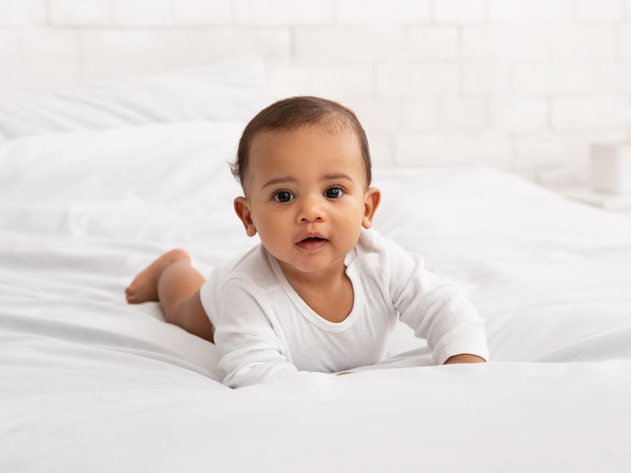Ein Baby krabbelt auf dem Bett.