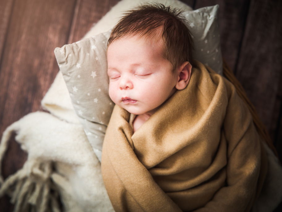 Ein Baby liegt in Decken eingewickelt und schläft.