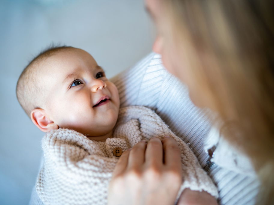 Eine Mutter hat ihr Baby auf dem Arm und es lächelt.