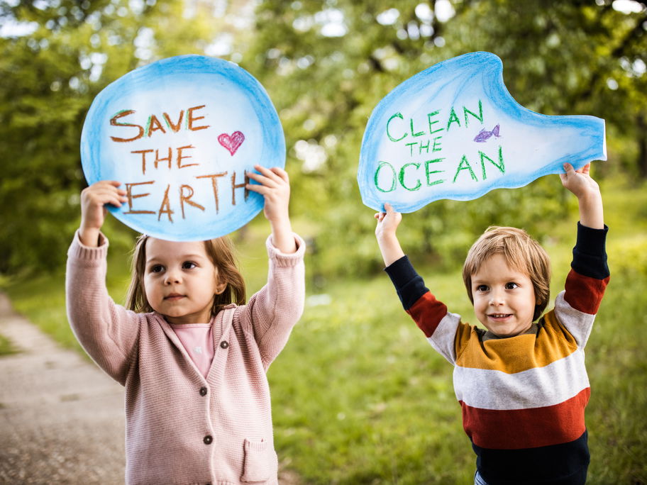 Ein Mädchen und ein Junge halten Schilder mit der Aufschrift "Save the Earth" und "Clean the Ocean".