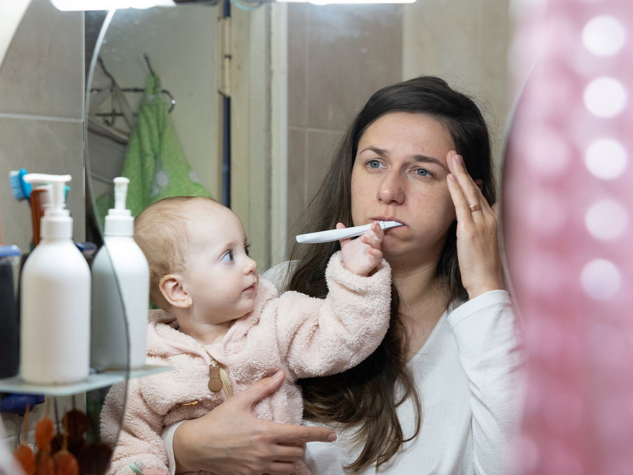 Eine müde Mama und ihr Baby im Badezimmer.