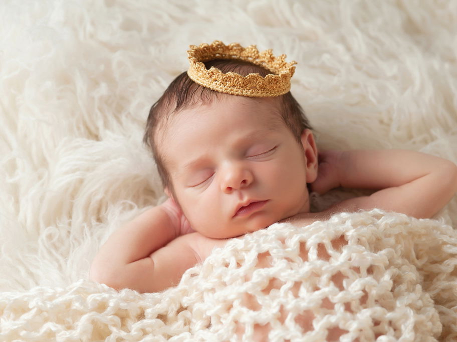 Ein Baby schläft mit einer Krone auf dem Kopf.