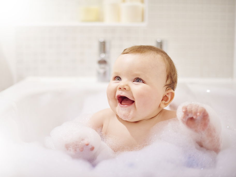 Baby sitzt in der Badewanne mit viel Schaum