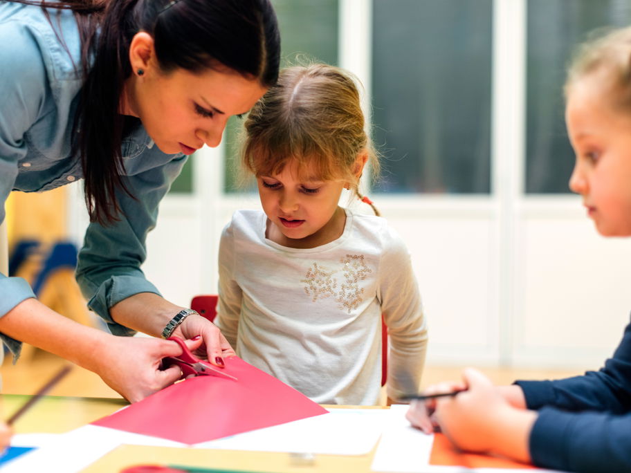 Erzieherin bastelt mit Kindern.
