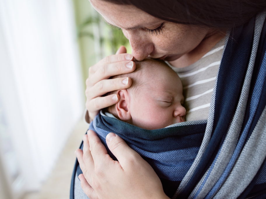 Mama hat Neugeborenes in Babytrage