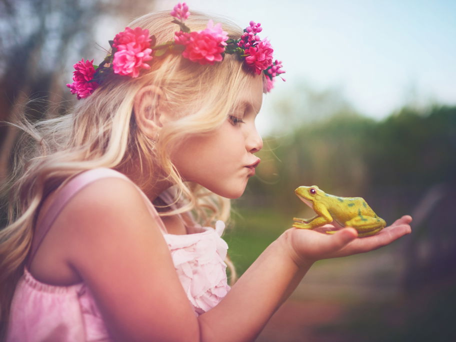 Kleines Mädchen küsst einen Frosch.