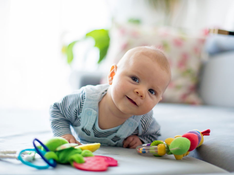 Ein Baby liegt auf dem Sofa und spielt.