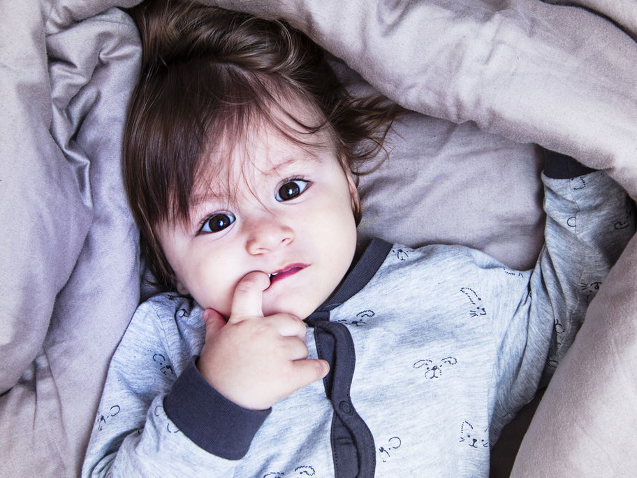 Ein kleines Kind liegt im Bett und kann nicht einschlafen.
