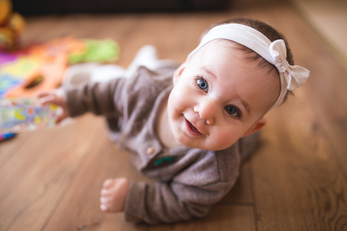 Ein Baby krabbelt neben Spielsachen auf dem Boden.