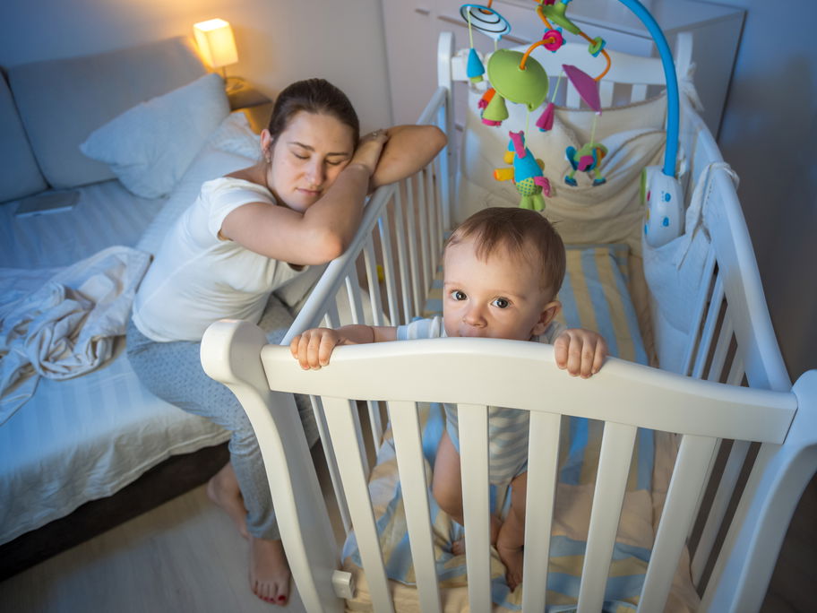 Baby steht nachts wach im Bett.