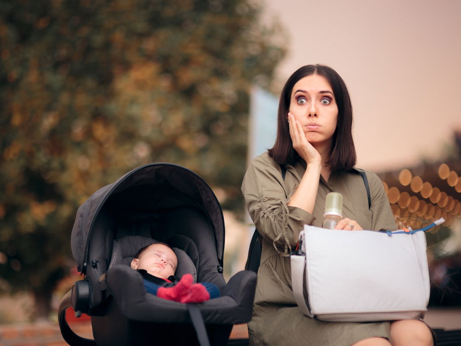 Vergessliche Mama sitzt neben Baby in Babyschale.