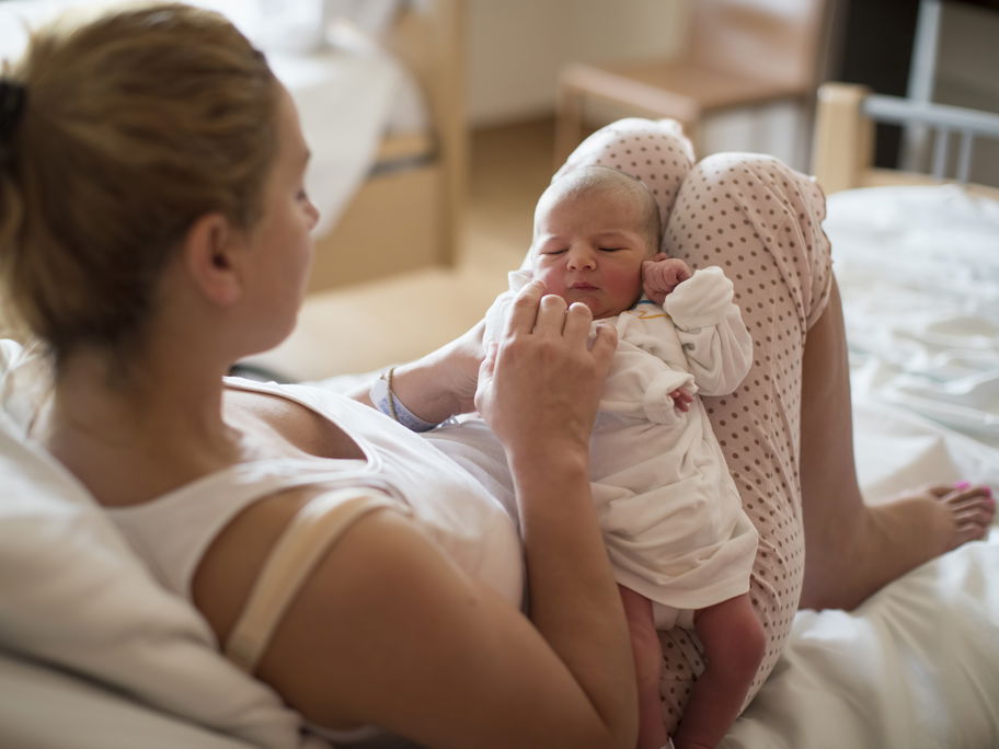 Eine junge Mama hält ihr Neugeborenes.