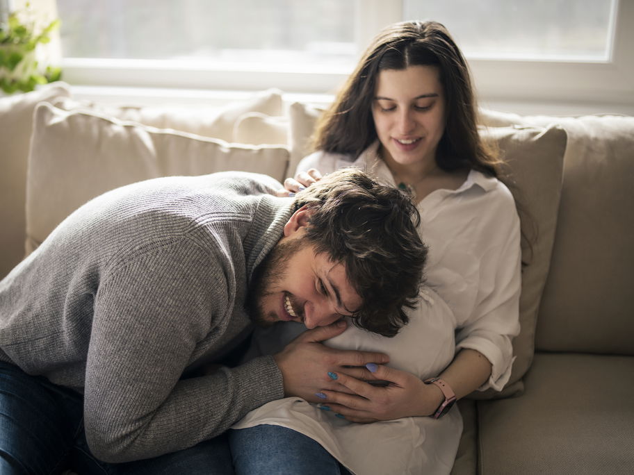 Werdender Papa legt Kopf auf Babybauch seiner Frau