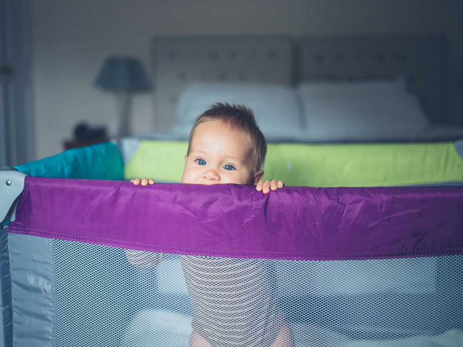 Baby schaut aus Reisebett