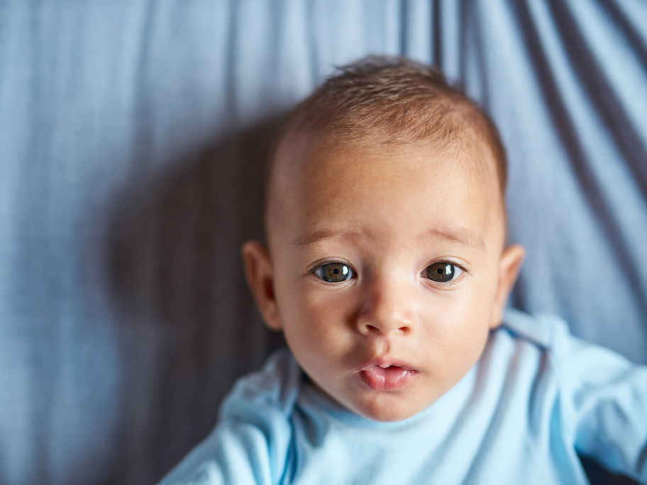 Ein kleines Baby, das süß in die Kamera guckt.