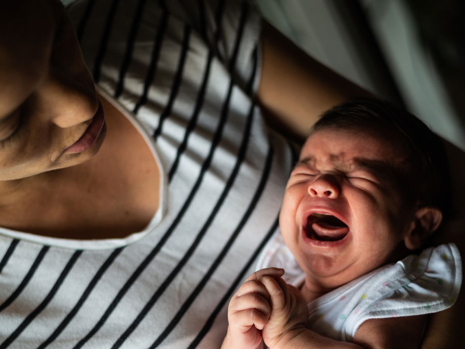 Mutter hält ihr schreiendes Baby im Arm.