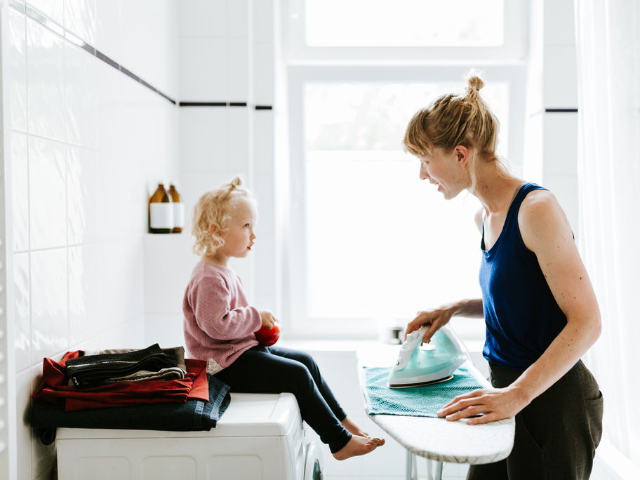 Mutter bügelt und spricht mit Tochter.