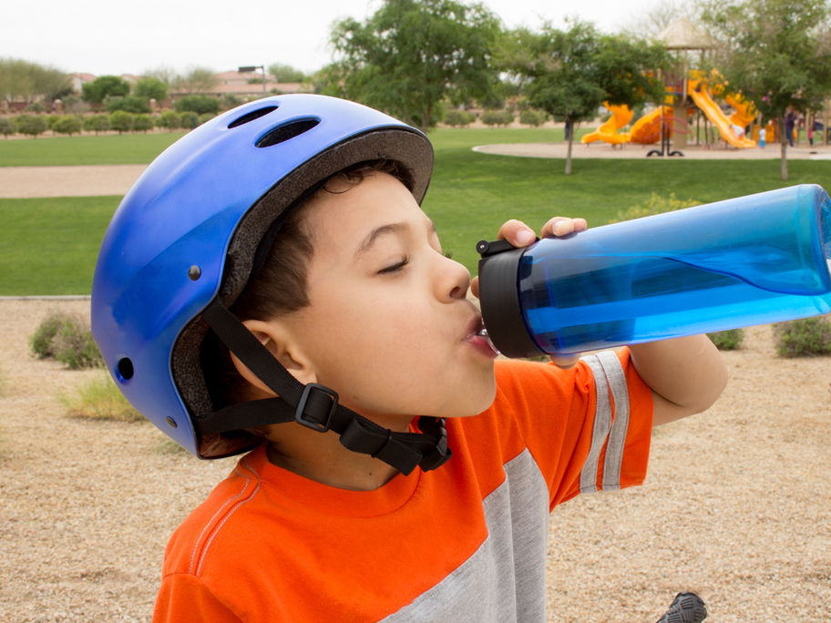 Junge trinkt im Freien aus seiner blauen Trinkflasche – doch wie reinigt man die am besten?