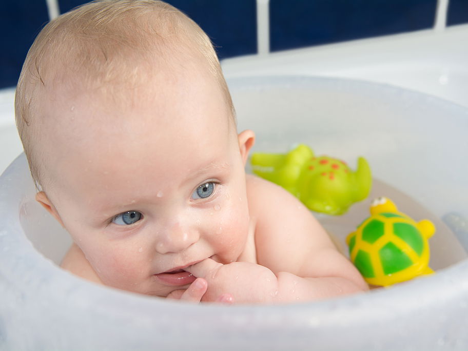 Kleiner Baby-Junge badet im Badeeimer nach Anleitung.