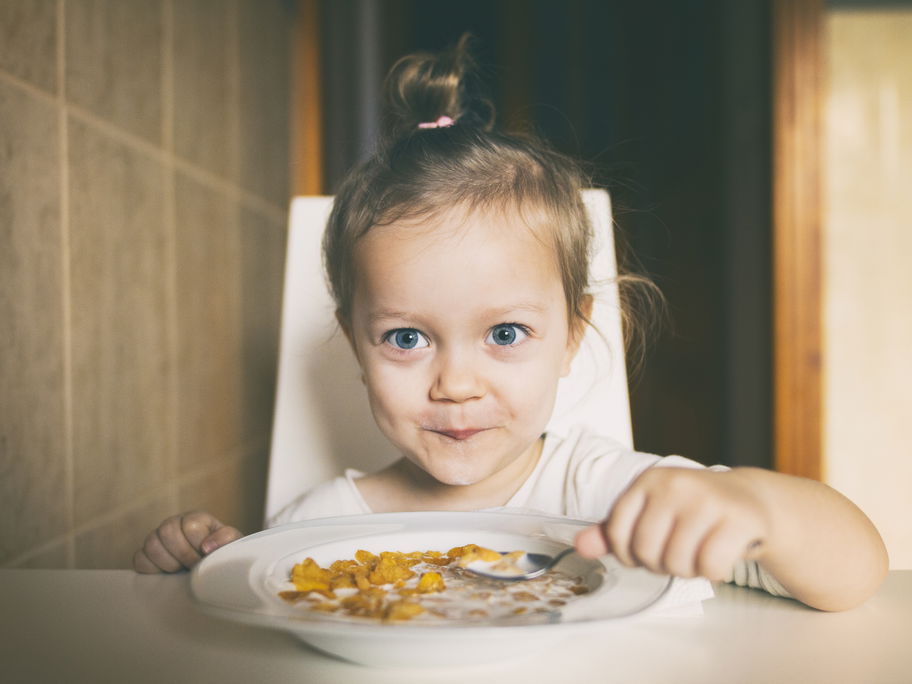 Mädchen freut sich über einen Teller Cornflakes